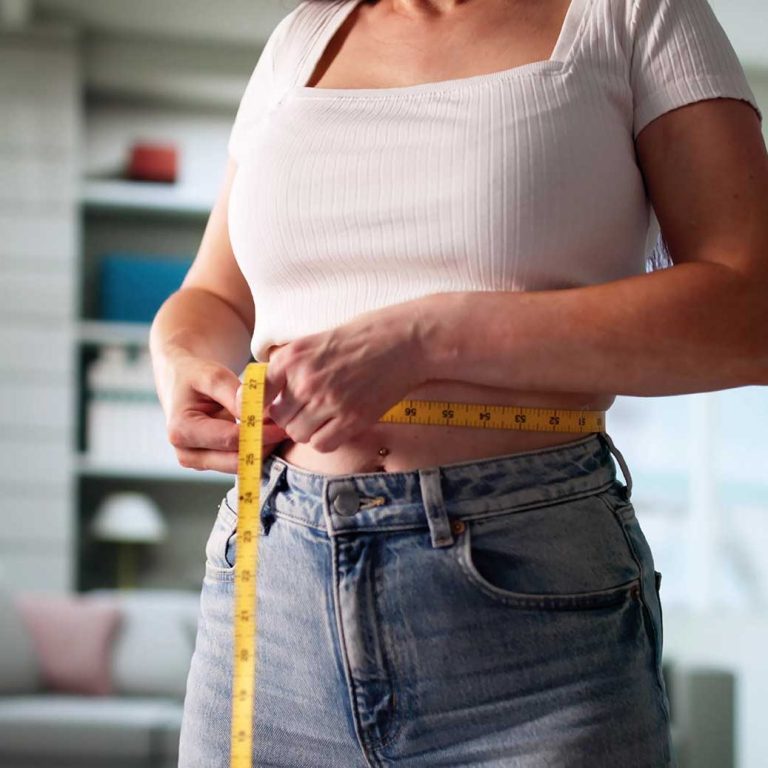 Junge Frau misst Ihren Bauchumfang